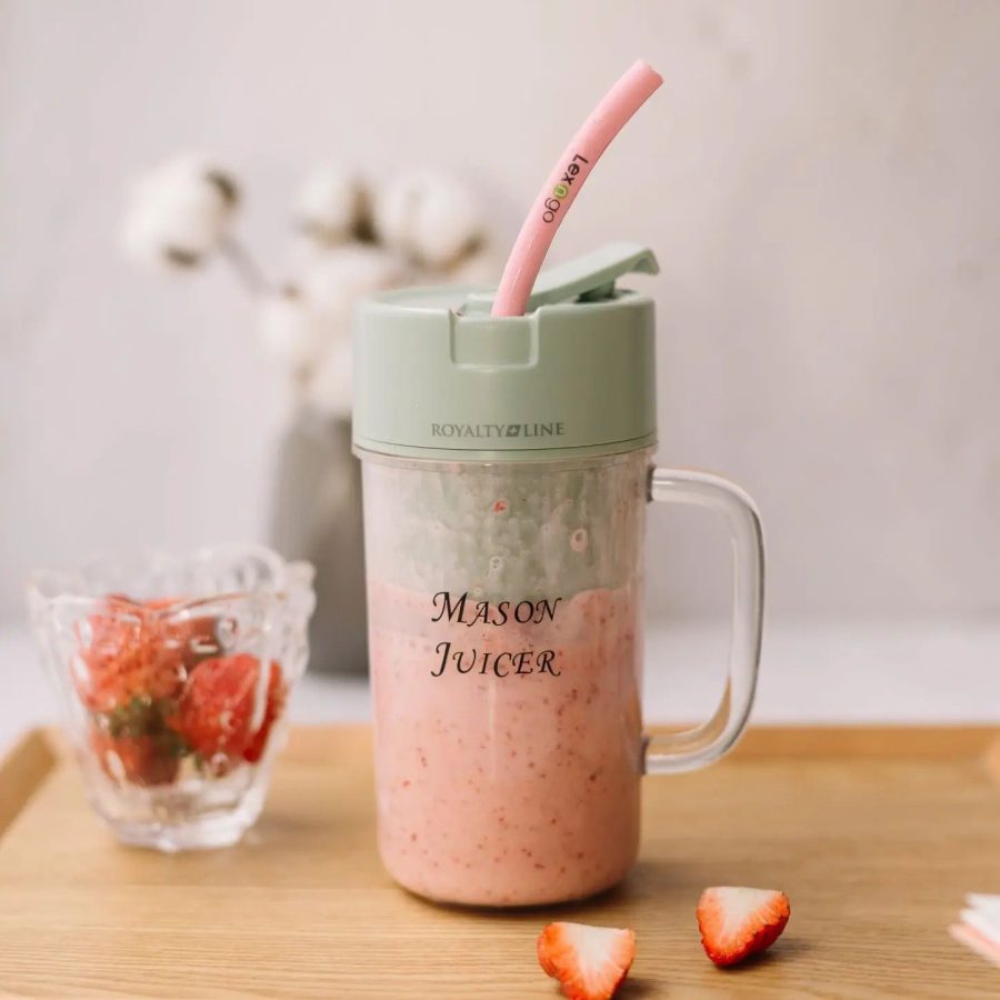Mason Juicer with pink smoothie and straw on a wooden surface with strawberries.